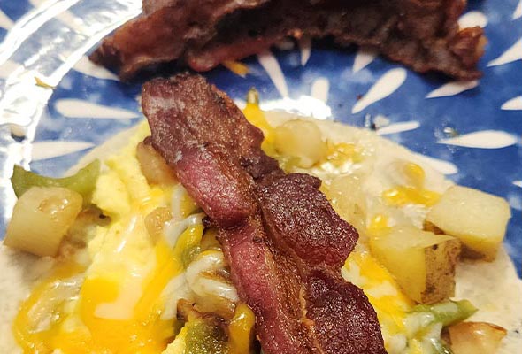 A breakfast taco or small burrito is served on a distinctive blue and white patterned plate.