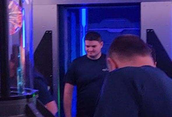 A man in a dark shirt is standing in a futuristic hallway