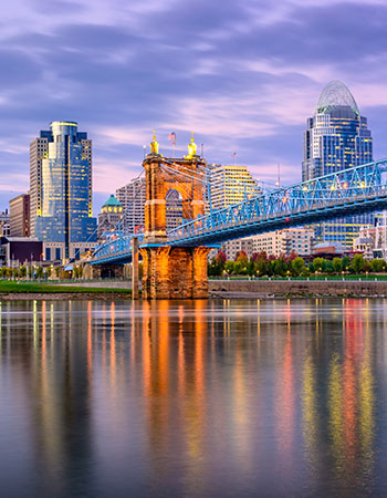 Scenic view of the Cincinnati skyline and the John A. Roebling Suspension Bridge reflecting on the Ohio River at sunset