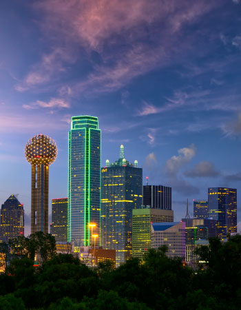 Nighttime view of the Dallas, Texas city center, with the iconic globe of Reunion Tower and brightly lit office buildings