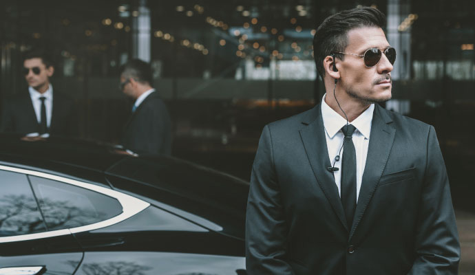 Executive protection security guard standing in front of a vehicle