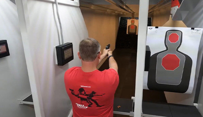 Man target shooting with a handgun in an indoor gun range lane